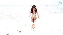 Standing at edge of water on beach in bikini long hair in pigtails